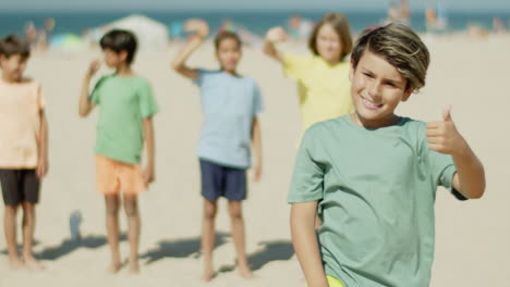 Vertical-motion-of-happy-boy-standing-on-shore-with-leg-on-ball
